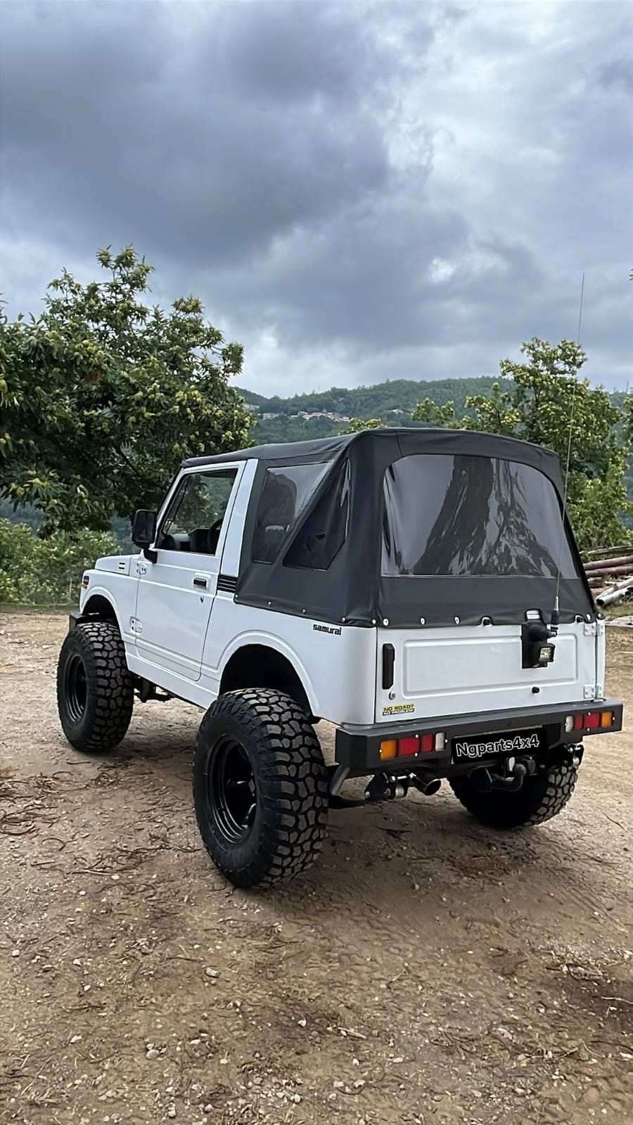 Suzuki Samurai bianco con capote nera e gomme tassellate in collina